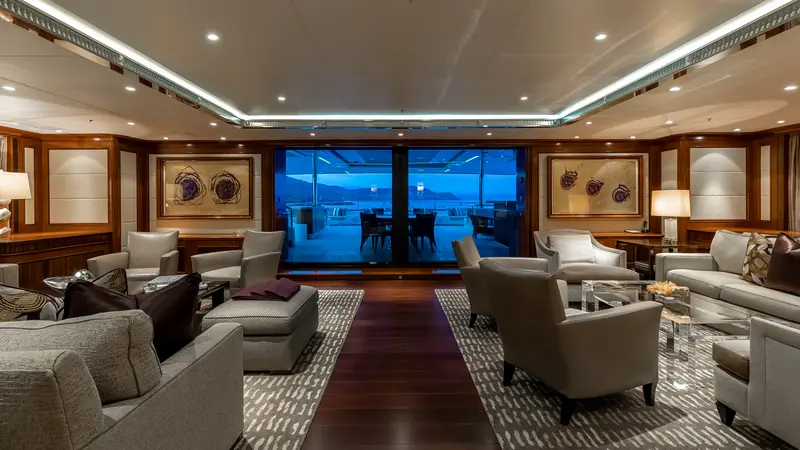The main saloon, looking aft toward the deck - one of the entertaining spaces that anchor the yacht's charter-style amenity list.