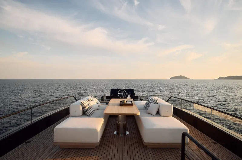 The flybridge aft lounge and wet bar, with the helm and a forward sunpad ahead of it - the BGX83's flybridge runs the full length of the superstructure.