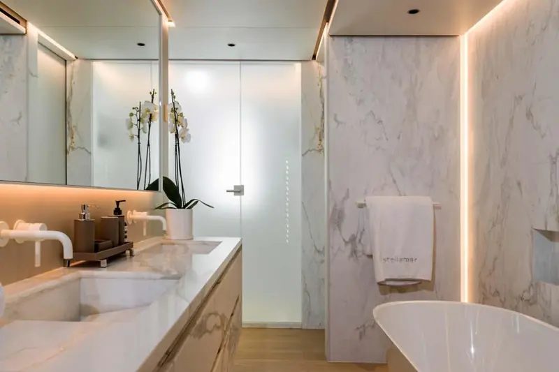 The owner's bathroom in book-matched marble, the towel by the freestanding tub monogrammed with the yacht's name.