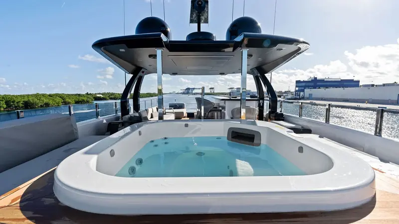 The flybridge bar and aft lounge, under the yacht's hardtop, looking out over open water.