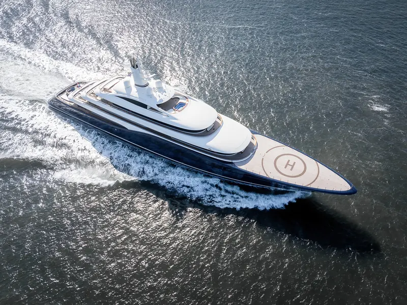 Destiny banks into her own wake on sea trials, the navy-blue hull and forward helipad seen from the air.