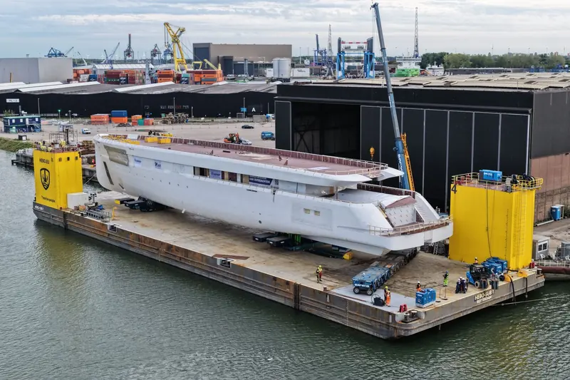 Project 832's bare hull on a HEBO transport barge in Rotterdam, still in primer with no name or owner attached.