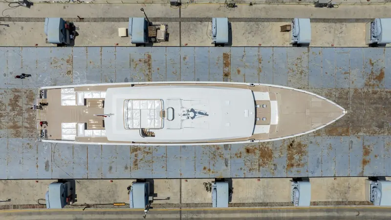 Looking straight down on the ship-lift platform. The layout answers the brief: a long open foredeck, teak side decks the full length, and a deckhouse that takes up far less of the boat than 45 metres usually allows.