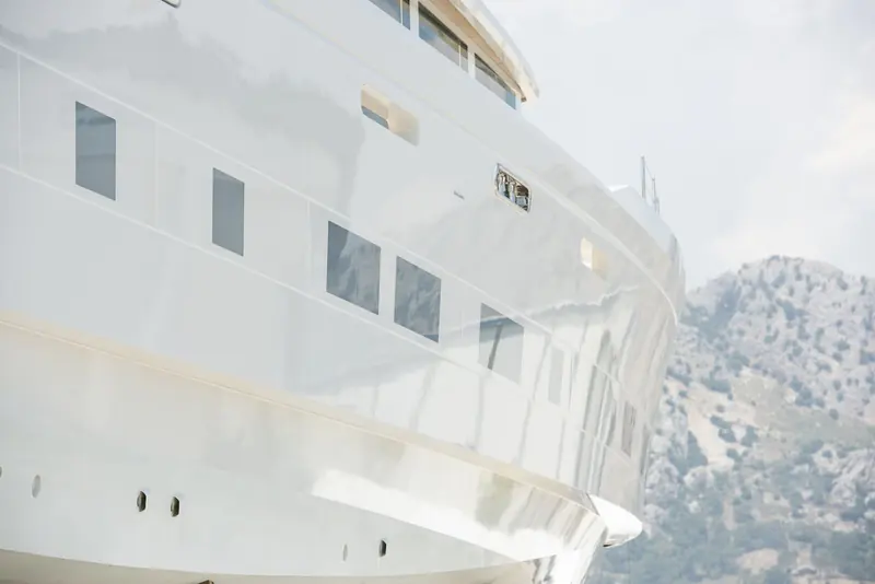 Topsides and the sheer under the Antalya hills. The low single-level deckhouse and the flush glazing are the visible cost of her 380 GT, which is modest volume for the length and entirely deliberate.