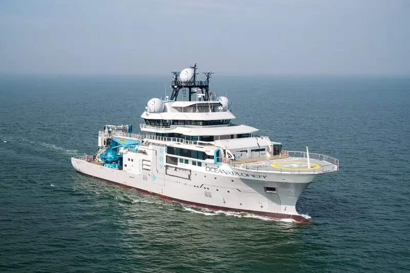 An aerial three-quarter view of OceanXplorer underway shows the helideck aft and the vessel's research-ship proportions, styled by the studio now trading as Gresham Marshall.