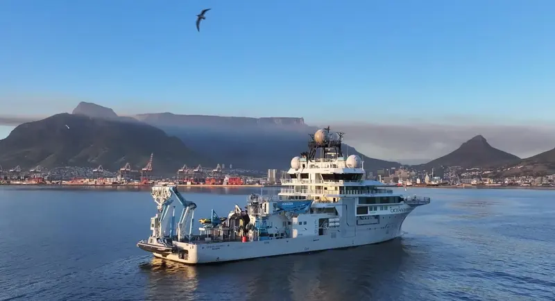 OceanXplorer approaches Cape Town with Table Mountain behind her, escorted by a small support craft as she nears port.