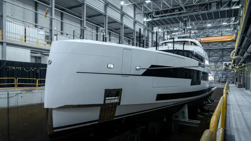YN 20857 in the covered hall at Oss shortly before her launch on 22 July 2026. The near vertical stem and the long, low run of glass are Omega Architects' work, and the whole hull and superstructure are aluminium rather than the steel a 57 metre would normally use.