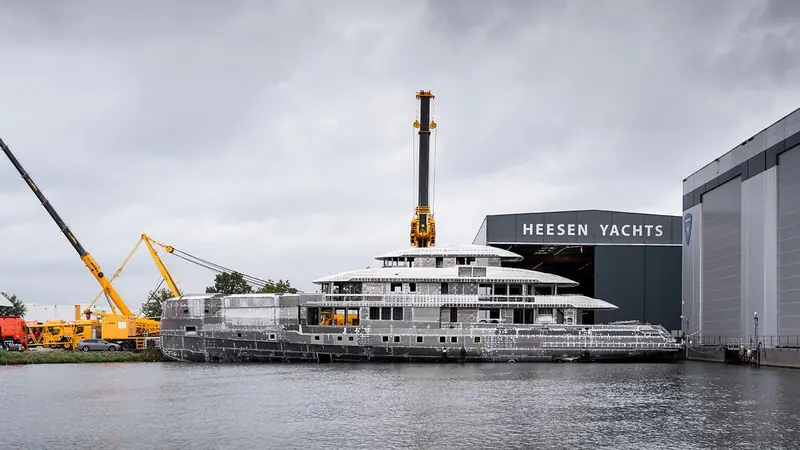 Afloat alongside the Heesen hall on the Meuse at Oss. Her 2.3 metre draught is shallow for the length, which is what lets a boat this size use anchorages that a deeper 57 metre has to pass by.
