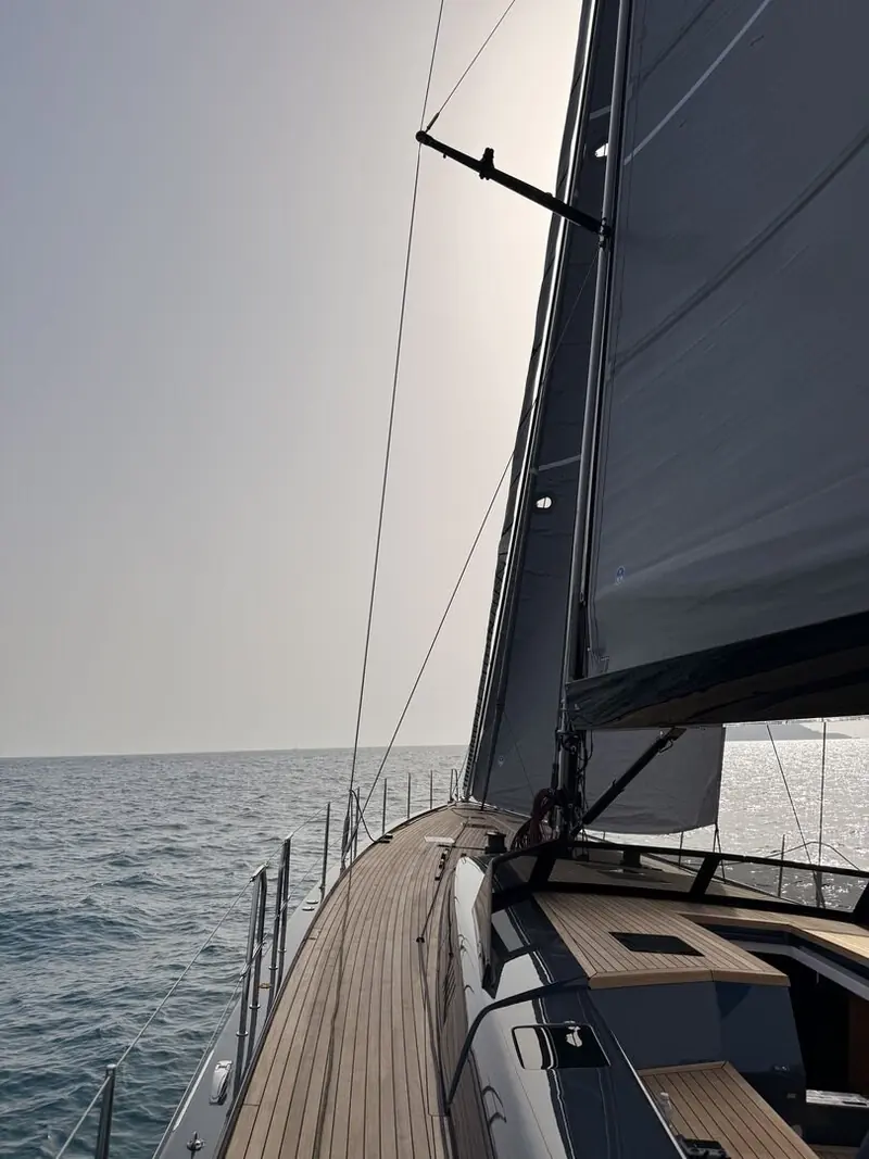 Looking forward from the cockpit, the headsail and wide, uncluttered side decks reflect the one-shot carbon vacuum-infusion build.
