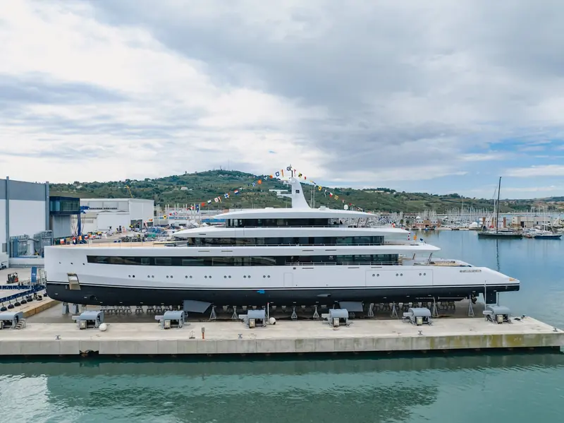 Belita alongside the fitting-out quay ahead of her launch, dressed overall with signal flags, Ancona's marina and hills behind her.
