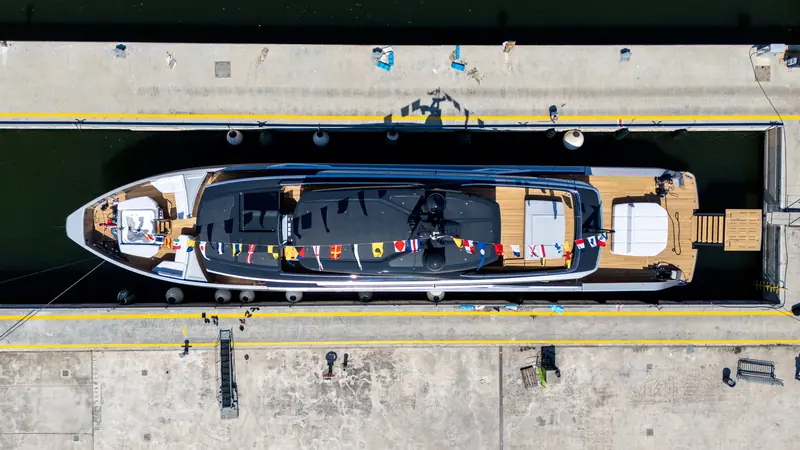 Seen from directly above, alongside at Ancona: a planing 38.8-metre hull with the beach club open aft and signal flags run the full length of the deck.