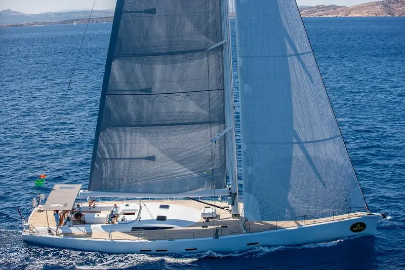 Ikigai upwind under a full main and genoa, one of a fleet of similar-sized yachts visible astern on the same course.