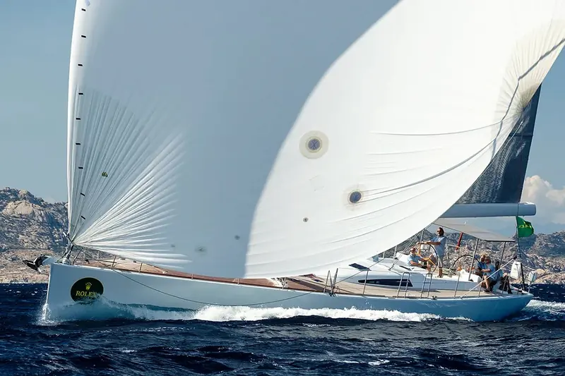 A reaching leg under spinnaker, the aluminium hull heeled hard and the deck crew braced against the rail.