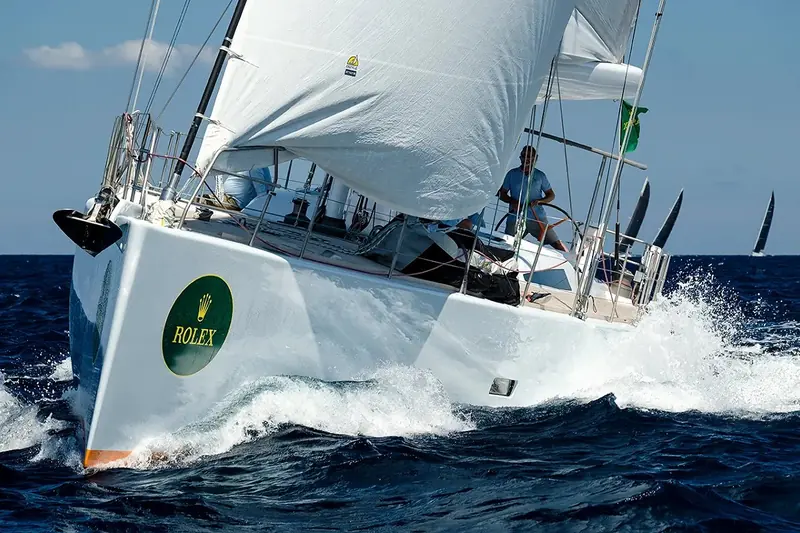 Ikigai driving hard downwind, spray breaking clear of the bow as the crew trims for speed.