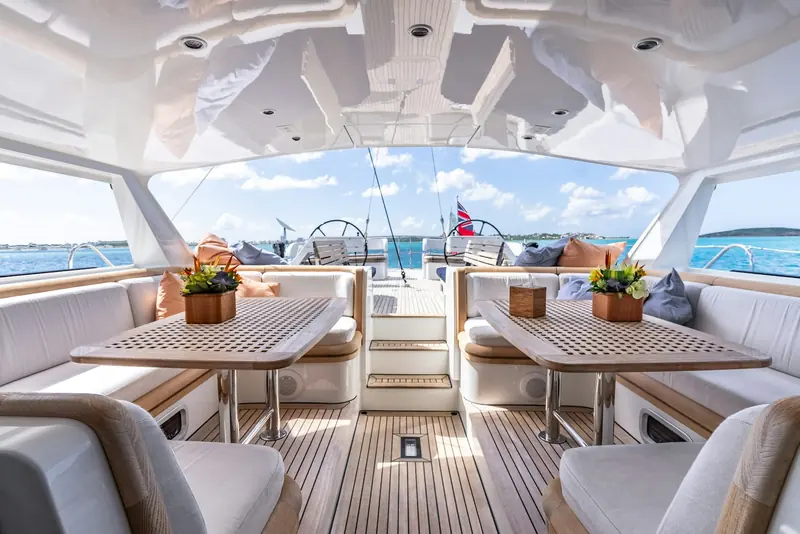 Twin dining tables in the aft cockpit, under a hardtop that opens the space to the stern view.