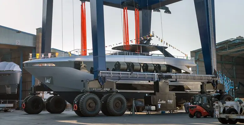 Waterborne after the naming ceremony in Viareggio harbour, flanked by the yard's travel lift fleet on the quay.