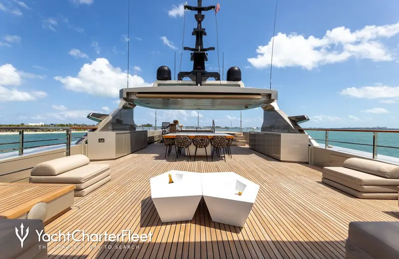 The sundeck aft dining table, shaded by the roof of her tender garage superstructure and framed by the mast and radar arch.