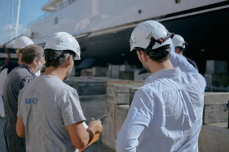 A refit team inspects work on a yacht's topsides at the Barcelona yard, one of the projects the concession extension to 2050 is meant to keep flowing.