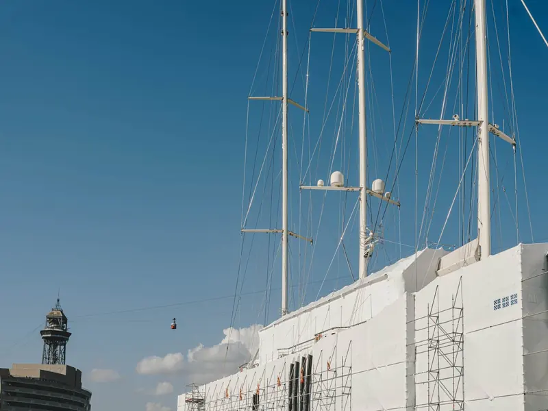 Sailing yacht rigs rise over the yard's dry dock building, part of the mixed sail and motor refit traffic MB92 Barcelona handles across its 126,500-square-metre site.