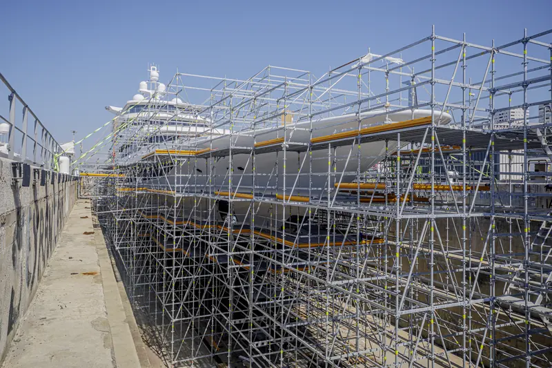 A superyacht fully enclosed in scaffolding during a refit - the kind of project Palumbo Upfit says can now move between any of its seven yards without a new contract.