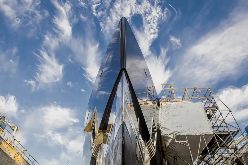 A yacht's mirror-polished bow rises above scaffolding in one of the network's dry docks, mid-refit.