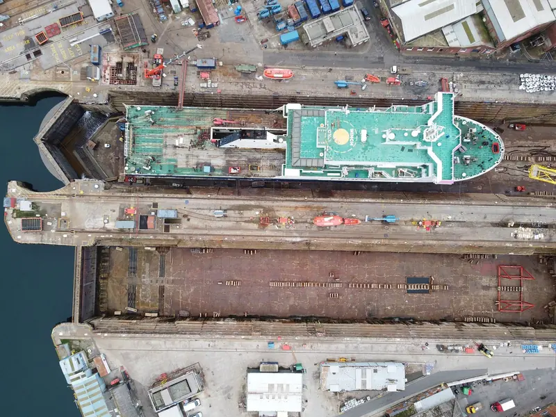 Looking straight down on the estate's graving docks, one occupied and one lying empty with the keel blocks already laid out. These are the wider Falmouth Docks facilities rather than Pendennis' own enclosed docks, and repairing structures like them is what the GBP 150m programme is for.