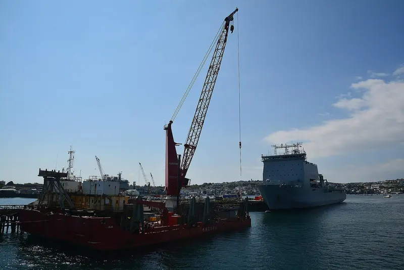A Royal Fleet Auxiliary landing ship stands out past the Fugro Seacore crane barge Excalibur. This is the honest picture of the estate: an owner's refit shares the water with defence, offshore and cruise work, and none of the GBP 150m is earmarked for yachts.