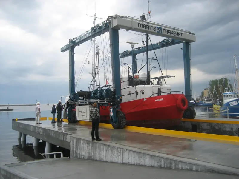 A Marine Travelift rated to 65 tonnes lifts a vessel clear of the water at Port Jastarnia, Poland - the same class of machinery superyacht surveys rely on, scaled down.