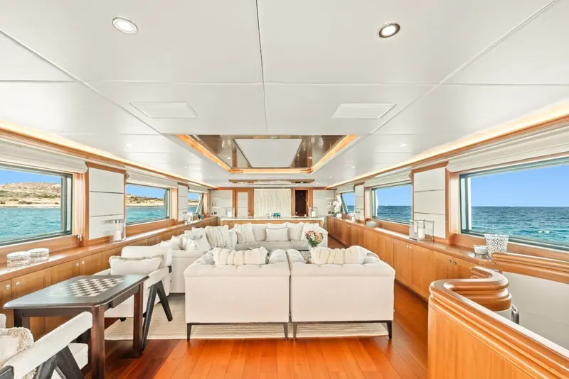 The main-deck salon, refitted in 2022, runs the full beam with wraparound sea views and a games table forward.