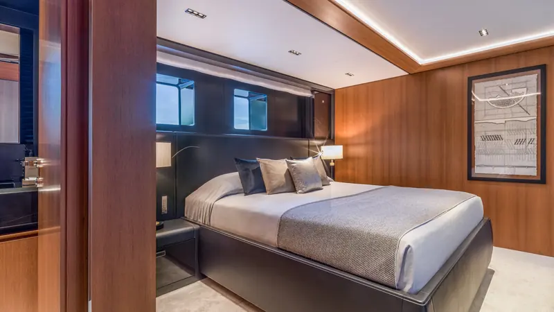 One of her four lower-deck guest cabins, in walnut and leather. Sairu sleeps ten guests in five cabins, with the owner's suite kept to itself on the main deck.