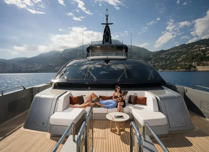 The bow lounge looking aft toward the bridge, Monaco's harbour and hillside behind - Riva's own launch photography rather than an independent sea trial.