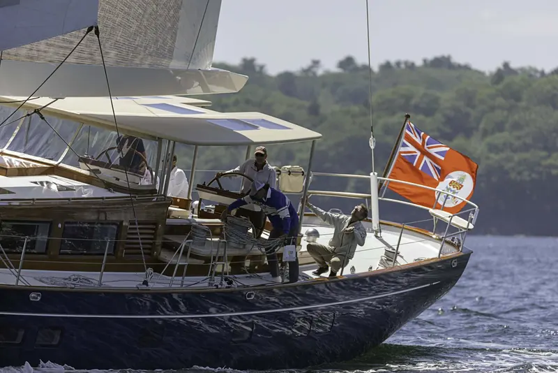 Crew at the helm and coachroof winches during sail trials - the deck layout keeps sail handling centralised for a small watch.