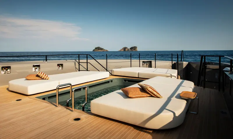 One of Heed's two pools, framed by sun pads and teak decking, with rocky islets on the horizon.
