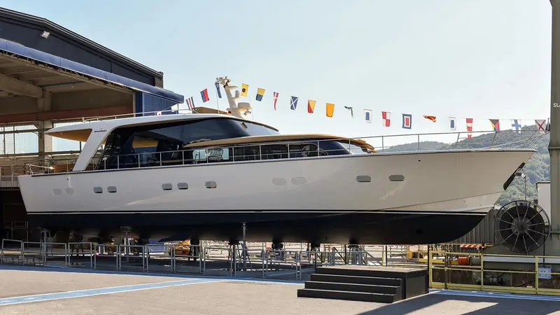 SHE on the travel lift at Sanlorenzo's Ameglia yard on the day of her launch, signal flags strung stem to stern - the yard's own send-off for every hull, not staged for this one.