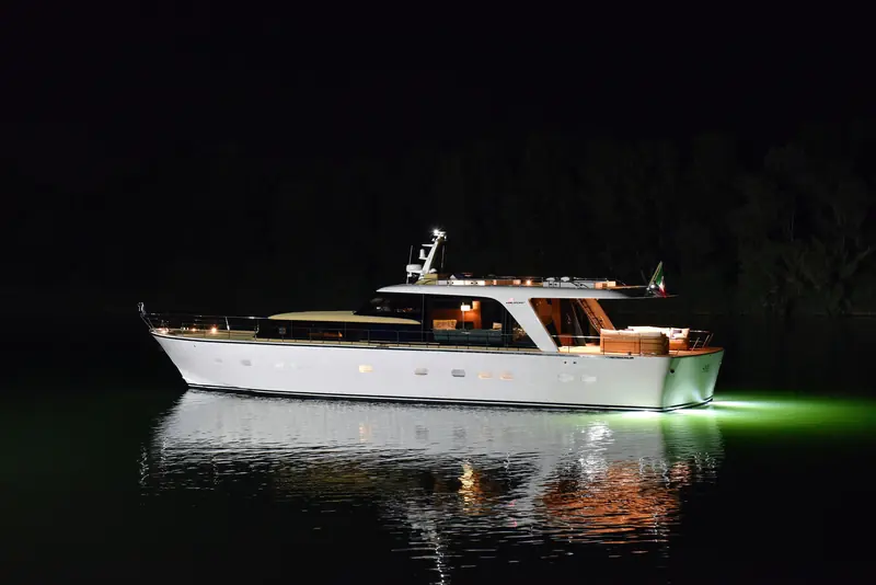 SHE afloat after dark, her name lit across a transom drawn from 1960s navetta lines rather than the flat, glazed sterns most 2026 yards are building.