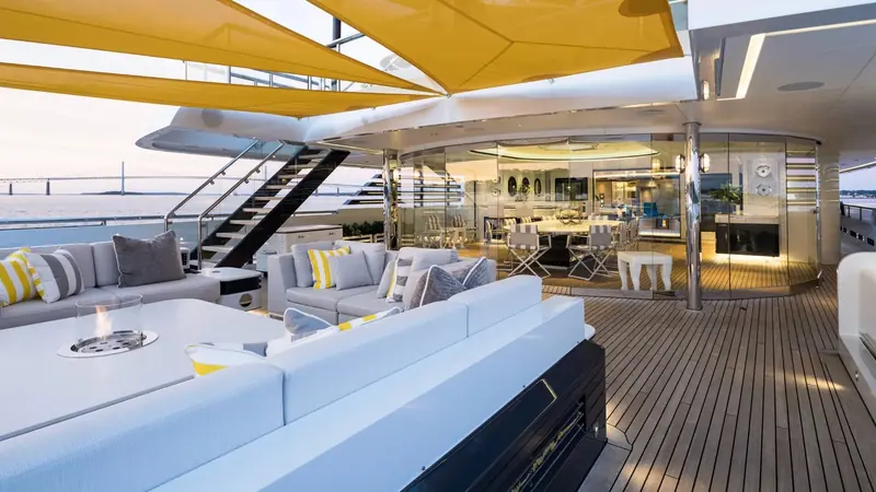 The main deck bar and lounge, glass-walled and open to the aft deck, with Newport's Pell Bridge visible astern.
