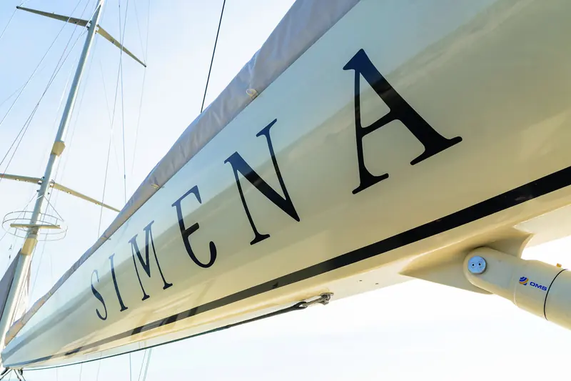 Her name on the hull, shot from beneath the boom. Taka Yacht Design drew both the naval architecture and the exterior.