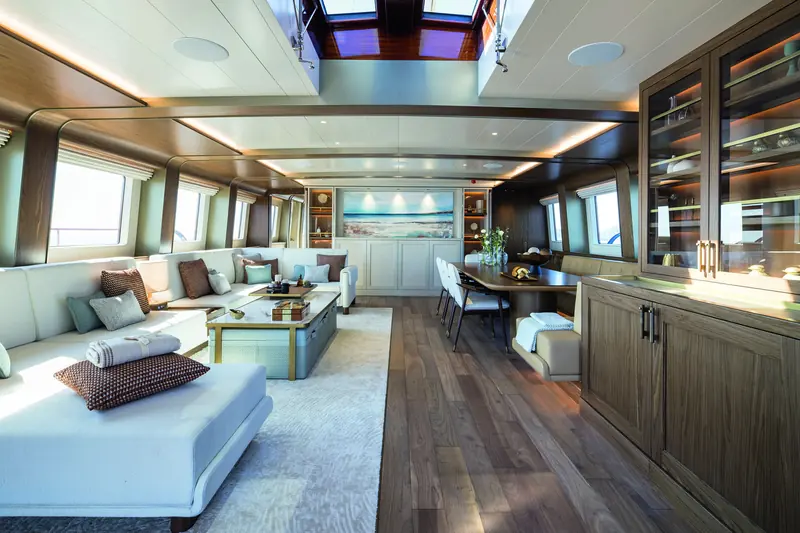The dining table and salon, with doors open to the aft deck. Design Unlimited, under associate designer John Everett, fitted the interior to a private-ownership standard rather than a charter-heavy specification.
