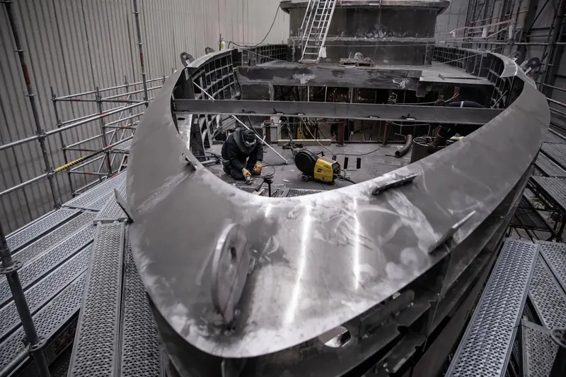 A welder works inside the freshly formed bow section of the 42M's steel hull, shot by Emre Boyoglu at Sirena's inland Turkish hall.