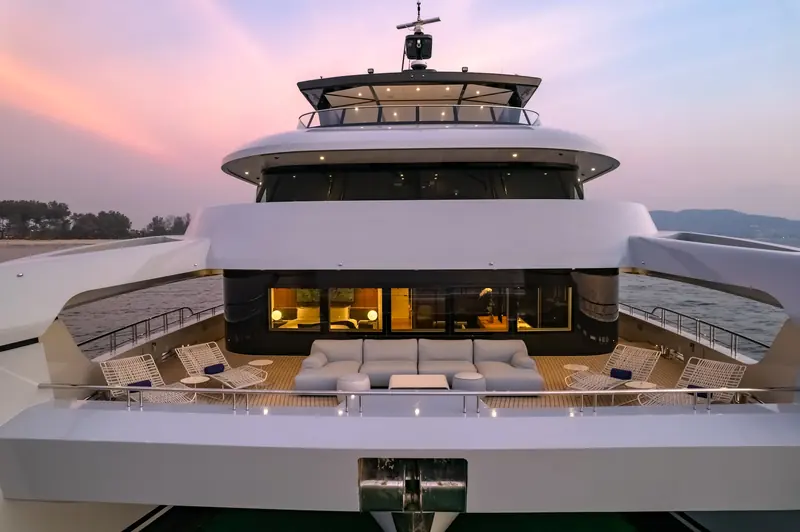 SpaceCat at anchor at sunset, three decks and a 13.3-metre beam giving her more open profile than a monohull near her length.