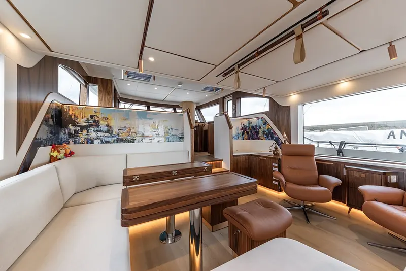 The lower saloon, one deck below the galley, showing the asymmetric layout's full-width seating with no side-deck corridor cutting across it.