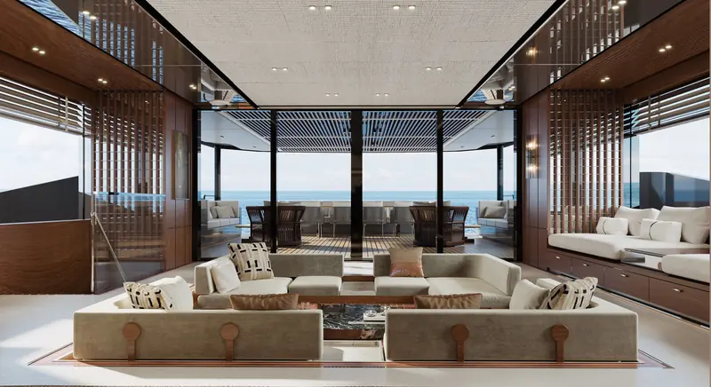 Maai's main-deck saloon, shown as a sunken lounge with low seating, timber screens and a view aft to the sea.