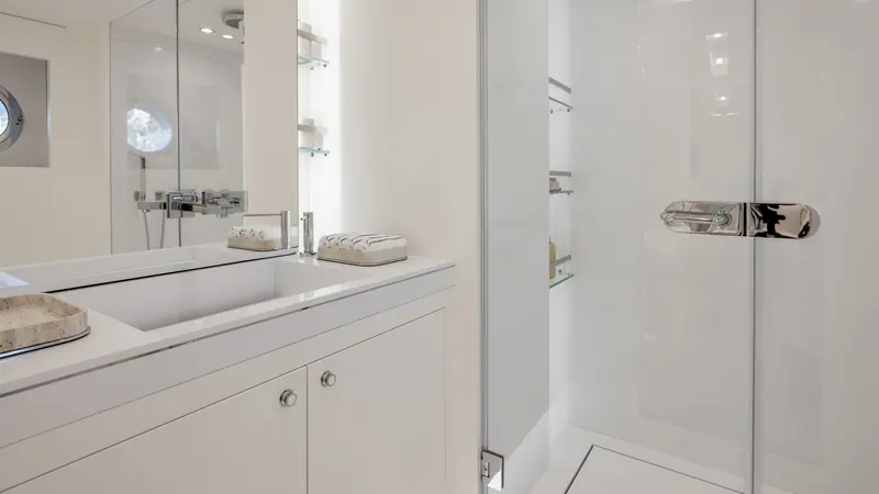 A guest ensuite bathroom finished in white stone and glass.
