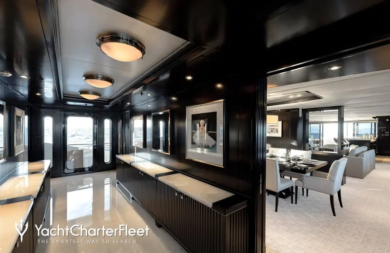 A corridor lined in black lacquer and more Deco-era photographic prints, leading aft to the dining room.