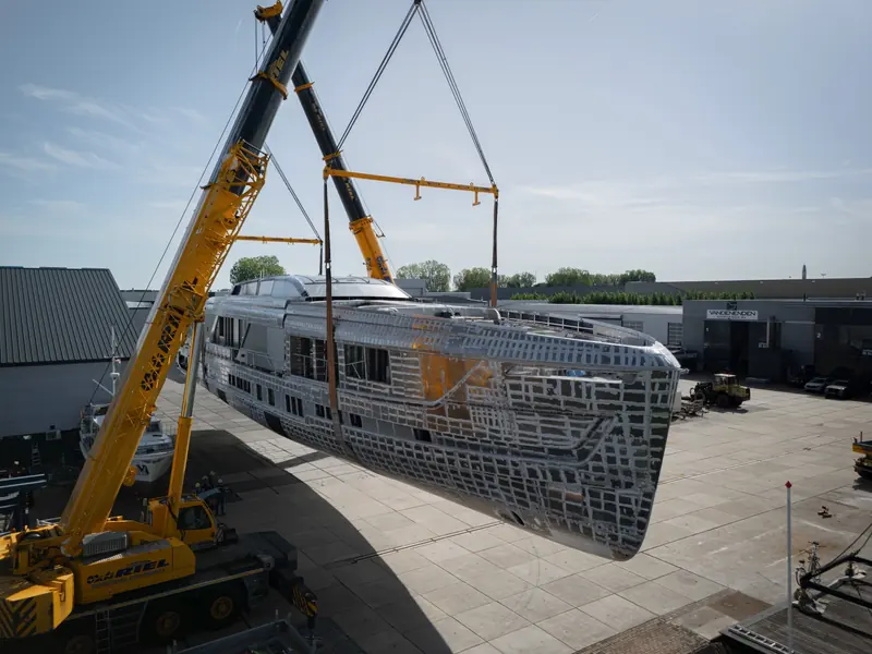 Her bow section swings from the crane slings, with the stepped aluminium plating clearly visible.
