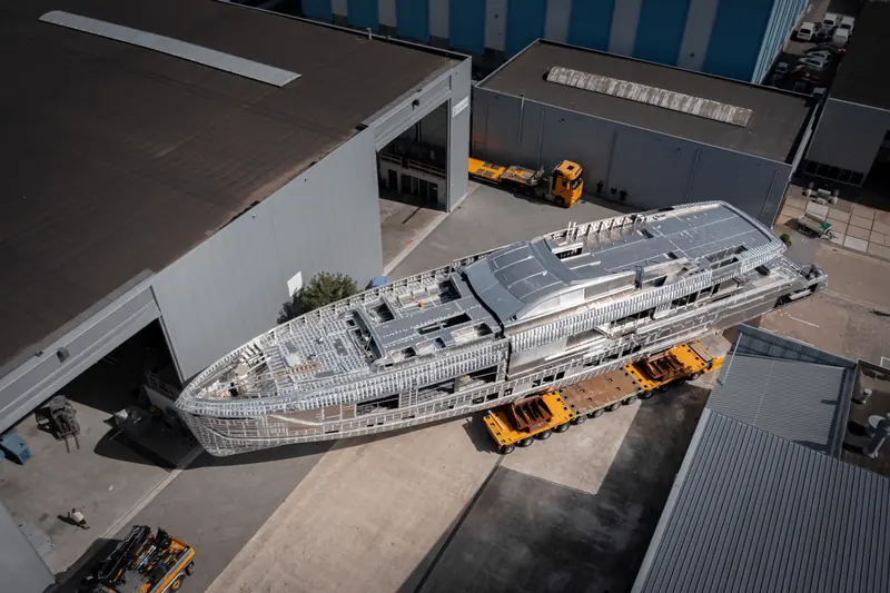 From above, Zen rests on her transporter beside the build hall with the open deck areas of the superstructure visible.