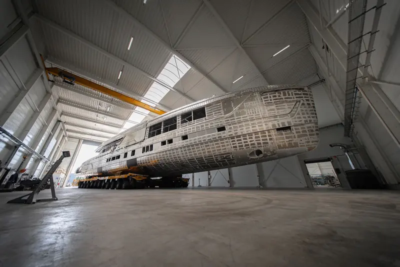 Inside the Waalwijk build hall, Zen's aluminium hull and superstructure rise above the concrete floor.