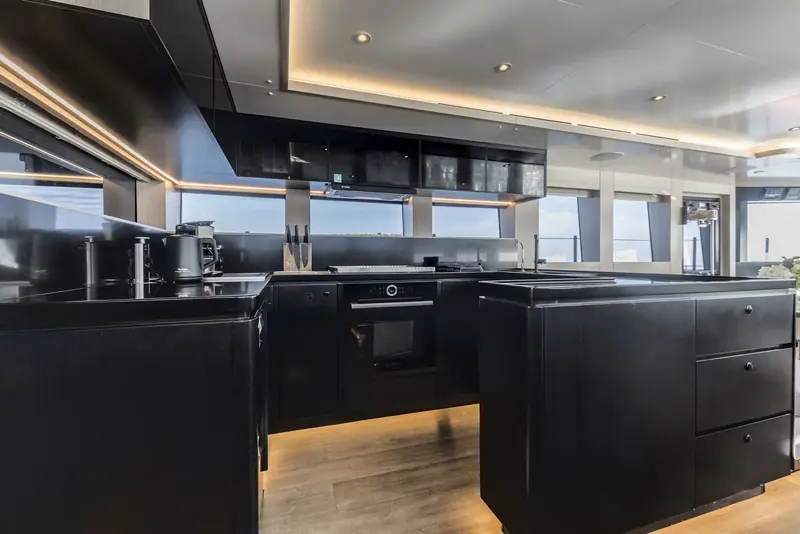 The galley, finished in dark cabinetry by interior designer Arista Marine, sits amidships rather than aft, ahead of the machinery space.