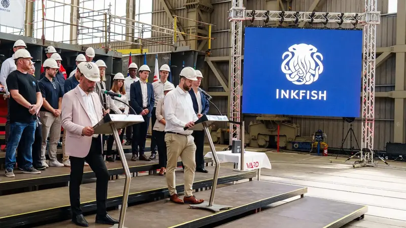 Vard executives address the ceremony beneath Inkfish's kraken logo, the steel sections of the 100-metre hull visible behind the stage.
