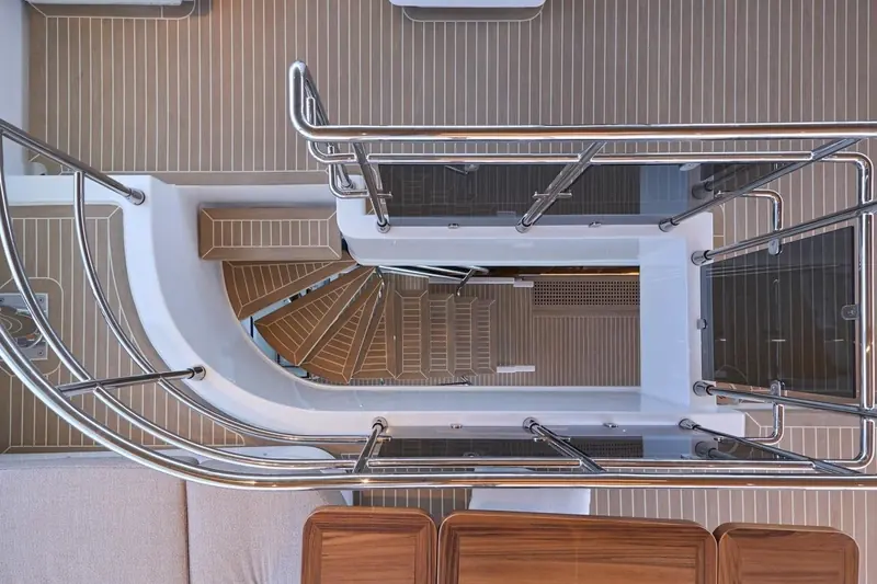 The spiral stair down from the flybridge to the swim platform, one of the interior details Denison's current sale listing photographs in full.